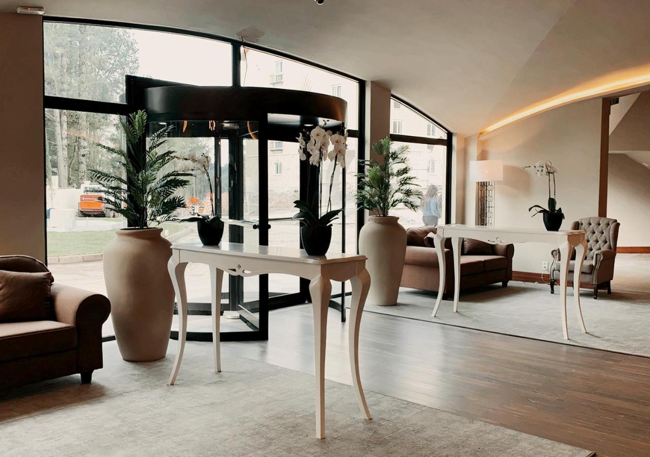 Buona Vitta Gramado Resort & Spa By Gramado Parks Kültér fotó The photo displays an elegant interior space, likely a hotel or a high-end lobby. In the foreground, there is a stylish table with a curved design, positioned near large glass doors leading outside. Flanking the table are two large planters with lush