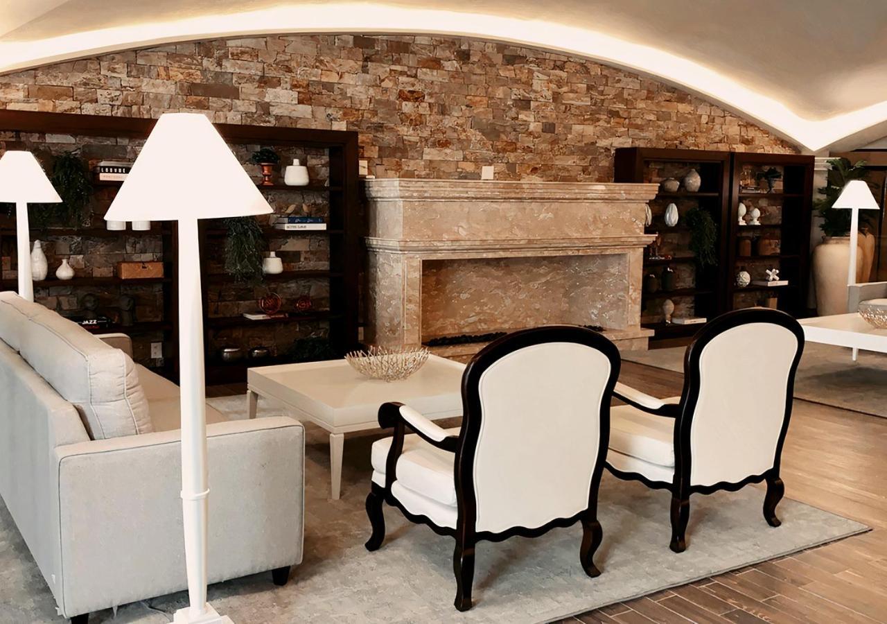 Buona Vitta Gramado Resort & Spa By Gramado Parks Kültér fotó The photo shows a stylish living room with a modern design. In the center, there is a light-colored sofa and two elegant white armchairs with black wooden frames. A coffee table is placed in front of the sofa. Behind them, there is a large, decorativ