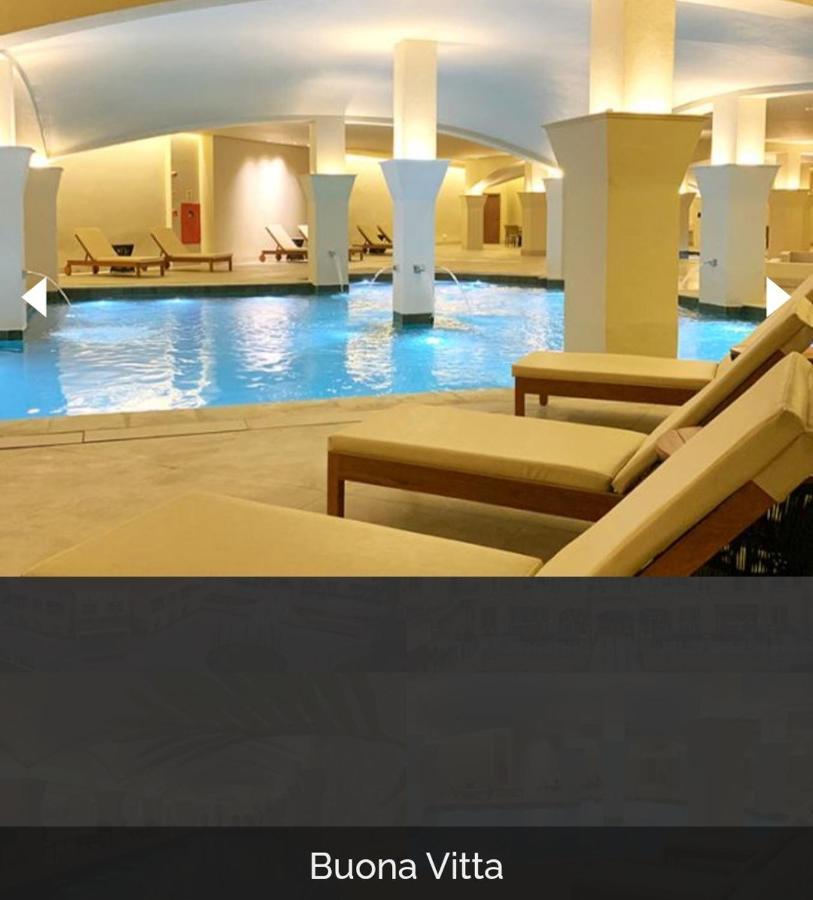 Buona Vitta Gramado Resort & Spa By Gramado Parks Kültér fotó The photo shows a tranquil indoor pool area, featuring a large swimming pool with clear blue water. Surrounding the pool are several lounge chairs made of light-colored wood, positioned for relaxation. The space is well-lit, with soft lighting highli