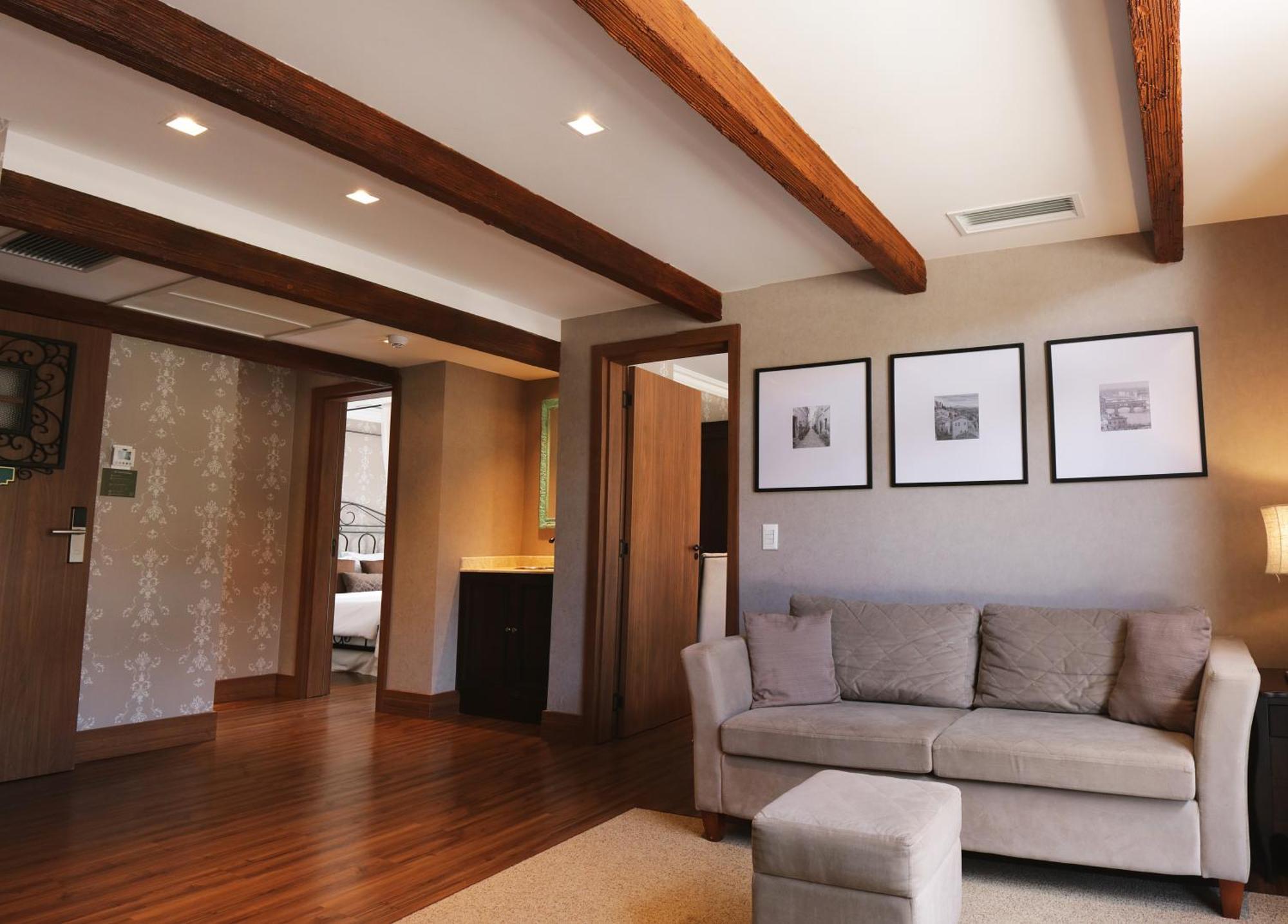 Buona Vitta Gramado Resort & Spa By Gramado Parks Kültér fotó The photo showcases a modern living space with a cozy and well-lit atmosphere. There are wooden beams visible on the ceiling, adding a rustic touch. The flooring is a warm-toned wood, contributing to the inviting feel of the room. 

On one side, ther