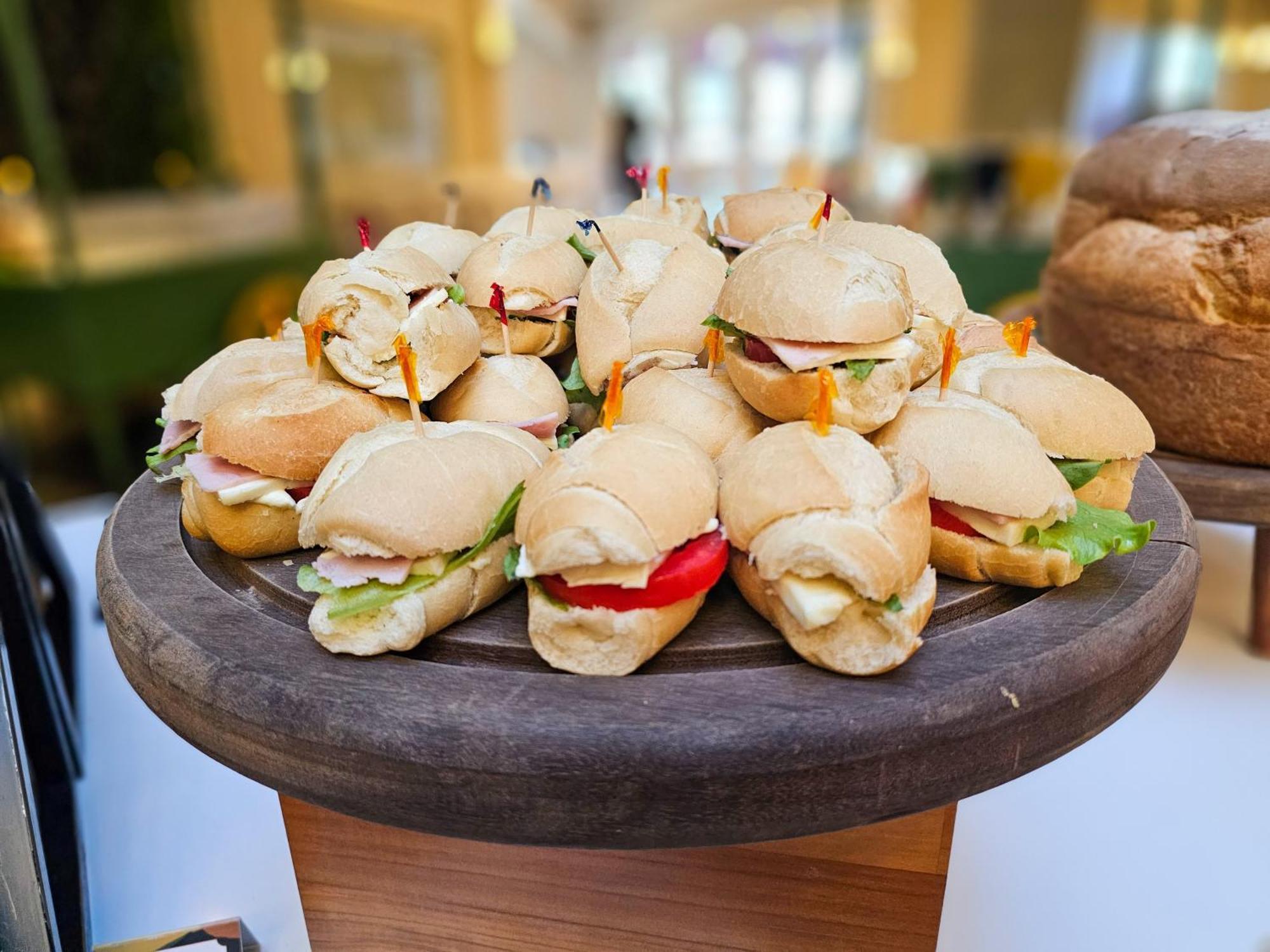 Buona Vitta Gramado Resort & Spa By Gramado Parks Kültér fotó The photo shows a platter of small sandwiches, likely sliders, arranged neatly on a wooden serving tray. These sandwiches have various fillings, including what appears to be ham, lettuce, and tomato. They are garnished with colorful toothpicks, and t
